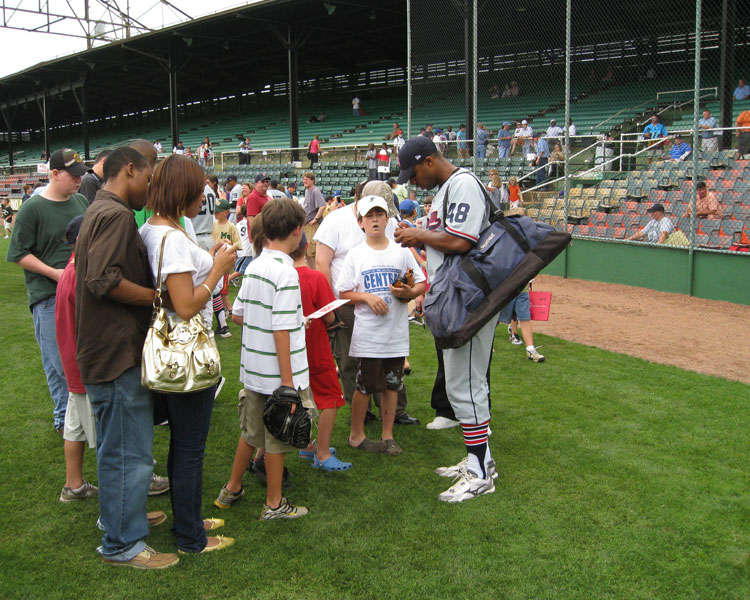 Players sign autographs on the field after the Rickwood Classic